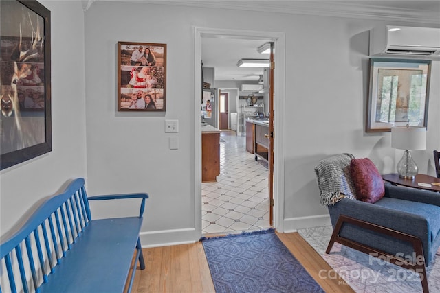 hall featuring a wall mounted AC, baseboards, crown molding, and wood finished floors