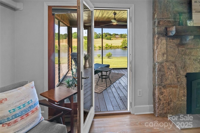 entryway featuring wood finished floors, a ceiling fan, a water view, and baseboards