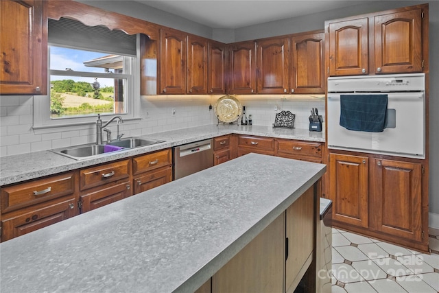 kitchen with oven, dishwasher, a sink, and backsplash