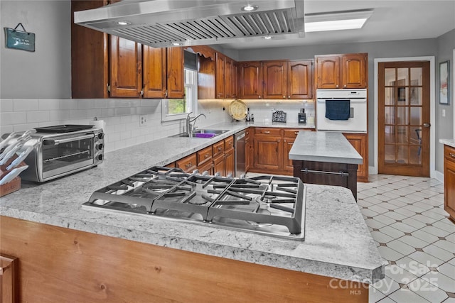 kitchen with stainless steel appliances, exhaust hood, a sink, light countertops, and light floors