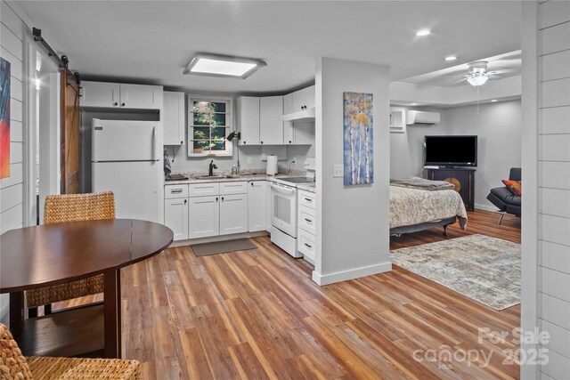 kitchen featuring white appliances, an AC wall unit, a barn door, ceiling fan, and light wood-style floors