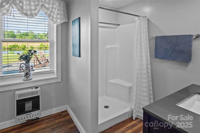 full bathroom with heating unit, wood finished floors, curtained shower, and baseboards