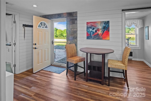 entrance foyer with wood finished floors, healthy amount of natural light, baseboards, wood walls, and heating unit