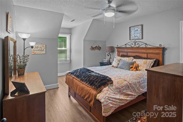 bedroom with light wood-type flooring, a textured ceiling, baseboards, and ceiling fan