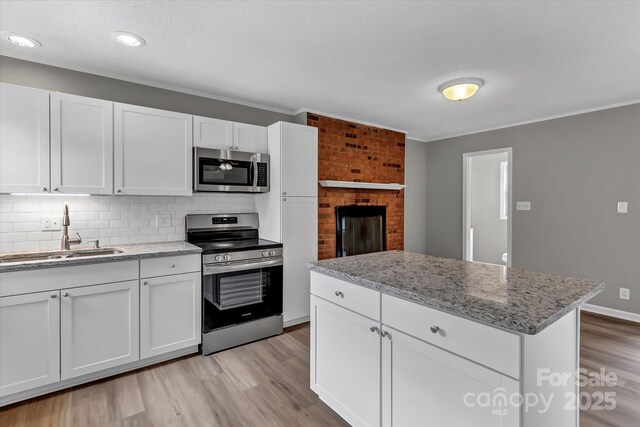 332 E Rebound Rd, Lancaster, SC 29720 - kitchen featuring appliances with stainless steel finishes, a sink, light wood-type flooring, white cabinetry, and ornamental molding