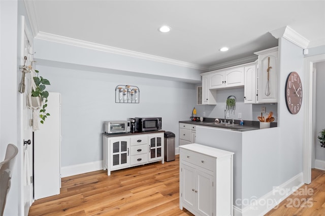 184 Quiet Cove Rd, Mooresville, NC 28117 - kitchen with stainless steel microwave, ornamental molding, white cabinetry, light wood finished floors, and baseboards
