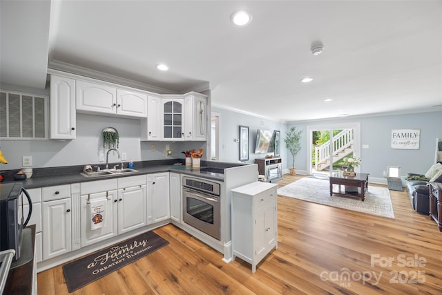 184 Quiet Cove Rd, Mooresville, NC 28117 - kitchen featuring oven, a sink, open floor plan, crown molding, and white cabinets