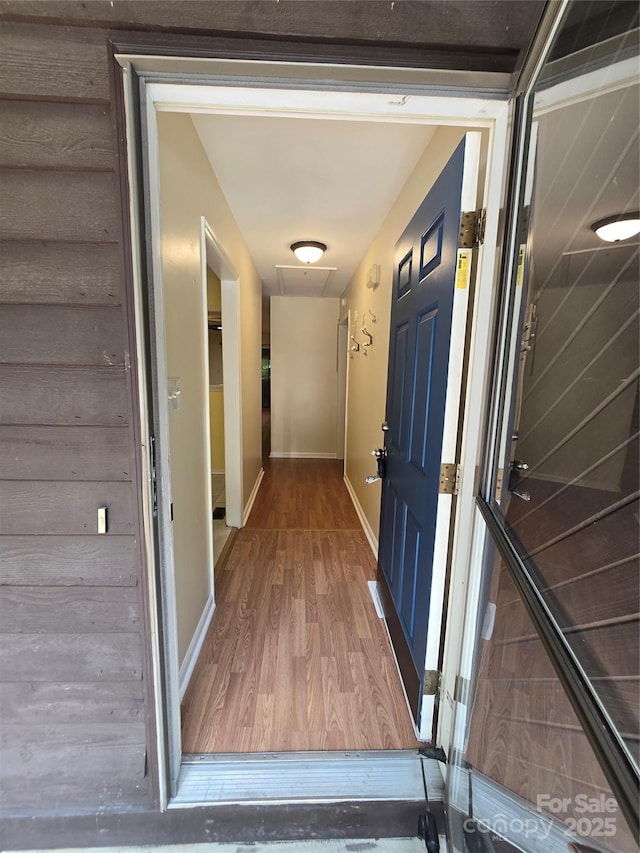 corridor featuring baseboards and wood finished floors