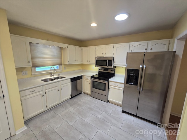 kitchen with light tile patterned floors, a sink, stainless steel appliances, white cabinetry, and light countertops