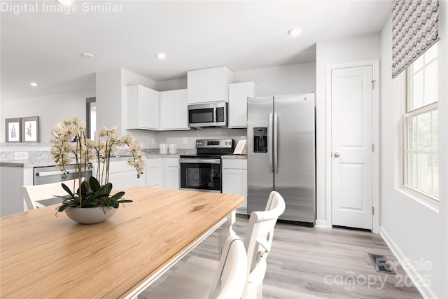 1430 Samuel St, Charlotte, NC 28206 - kitchen with stainless steel appliances, white cabinets, light wood-style floors, recessed lighting, and a peninsula