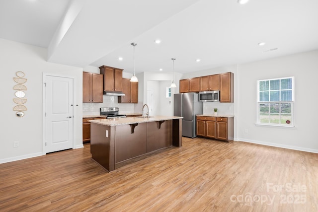 2012 Slippery Rock Ln, Monroe, NC 28112 - kitchen with stainless steel appliances, light wood finished floors, under cabinet range hood, a breakfast bar, and recessed lighting