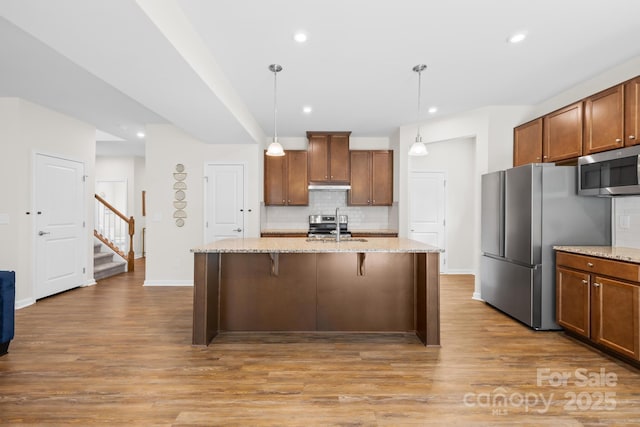 2012 Slippery Rock Ln, Monroe, NC 28112 - kitchen featuring stainless steel appliances, decorative backsplash, light wood finished floors, a kitchen bar, and recessed lighting