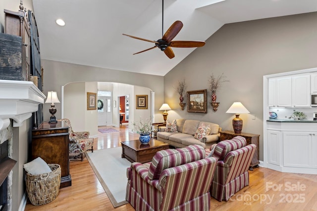 216 Cold Stream Way, Hendersonville, NC 28791 - living area featuring a ceiling fan, light wood-style flooring, high vaulted ceiling, arched walkways, and a fireplace