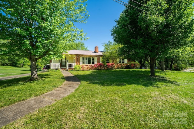 view of front of house featuring covered porch, a chimney, a front yard, and brick siding