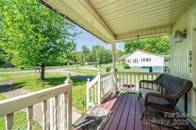 wooden terrace with covered porch and a yard