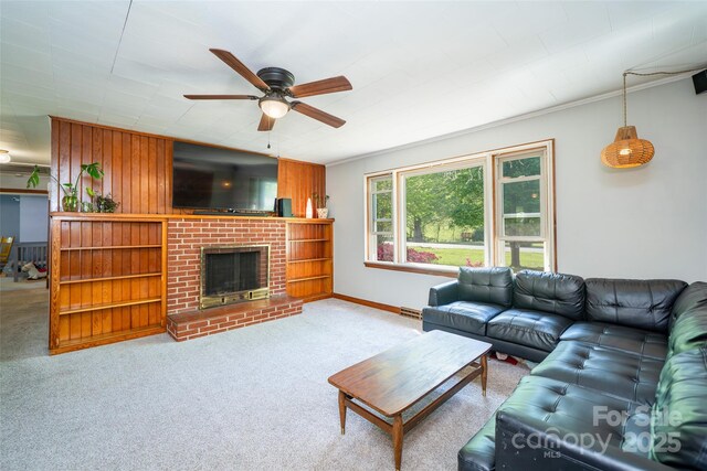 living area with a ceiling fan, carpet, a fireplace, baseboards, and wooden walls
