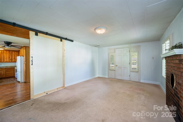 unfurnished living room with a brick fireplace, carpet flooring, baseboards, and a ceiling fan