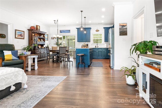 living area with ornamental molding, recessed lighting, dark wood-type flooring, and a chandelier