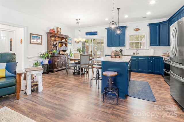 kitchen featuring blue cabinets, a center island, a breakfast bar, tasteful backsplash, and crown molding