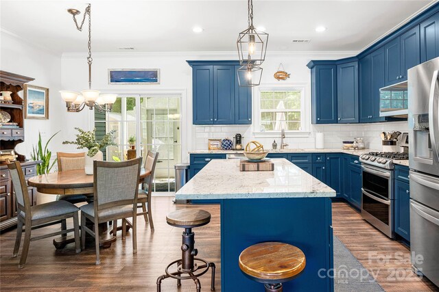 kitchen featuring blue cabinets, appliances with stainless steel finishes, a chandelier, dark wood finished floors, and ornamental molding