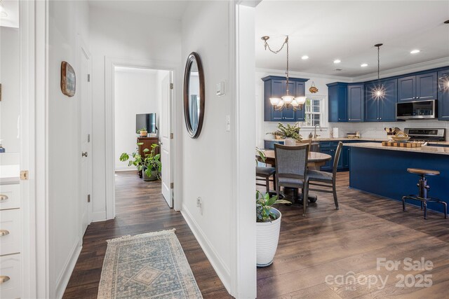 hallway with dark wood-style flooring, baseboards, recessed lighting, a sink, and crown molding