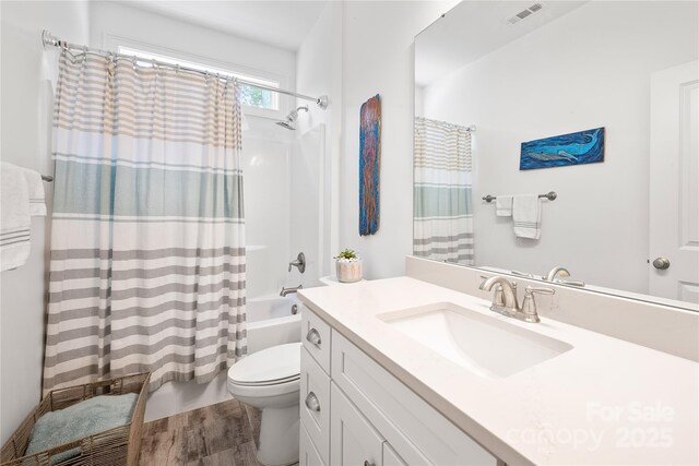 bathroom with toilet, shower / bathtub combination with curtain, wood finished floors, and vanity
