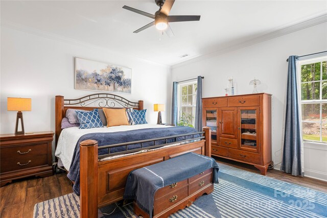 bedroom featuring dark wood-style floors, crown molding, and multiple windows
