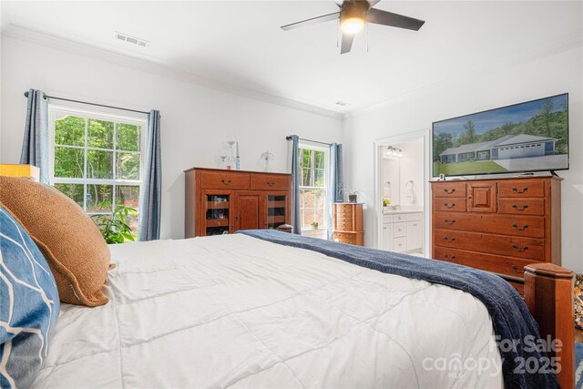 bedroom featuring crown molding, multiple windows, ensuite bath, and a ceiling fan