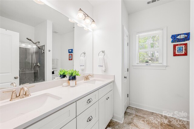 bathroom with a tile shower, double vanity, and baseboards