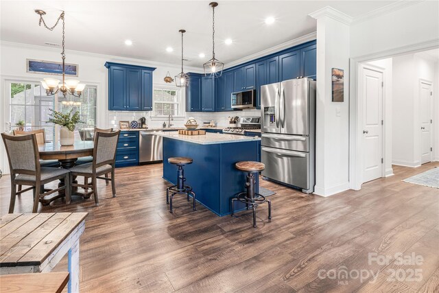 kitchen featuring stainless steel appliances, blue cabinets, crown molding, a sink, and a chandelier