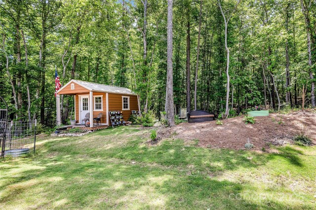 view of grassy yard with an outdoor structure and a wooded view