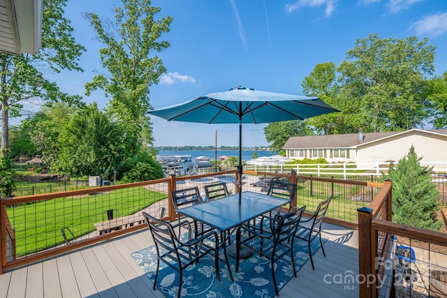 wooden deck with a yard, fence, a water view, and outdoor dining space