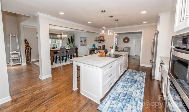 kitchen with light stone countertops, a center island, a kitchen bar, white cabinetry, and appliances with stainless steel finishes