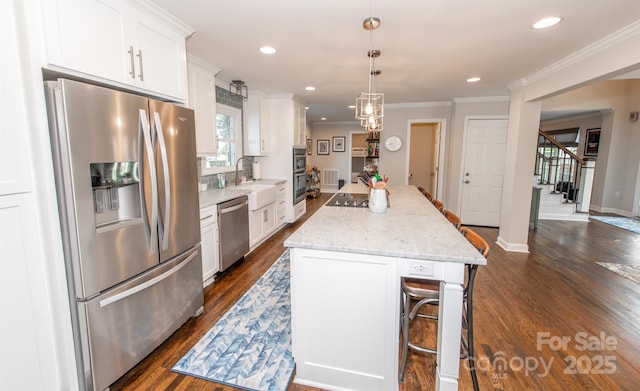 kitchen featuring dark wood-style flooring, a sink, white cabinetry, a kitchen island, and stainless steel appliances