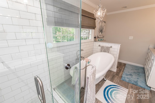 bathroom featuring wood finished floors, a stall shower, a notable chandelier, a freestanding bath, and ornamental molding