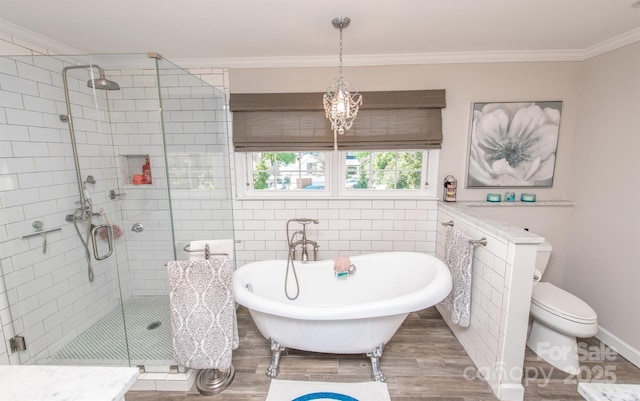 full bathroom featuring a stall shower, toilet, ornamental molding, a soaking tub, and wood finished floors