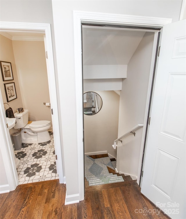 bathroom featuring crown molding, toilet, baseboards, and wood finished floors