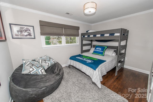 bedroom with wood finished floors, visible vents, baseboards, and ornamental molding