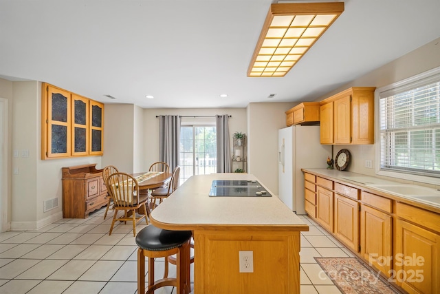 14340 Kendalton Meadow Dr, Mint Hill, NC 28227 - kitchen featuring black electric stovetop, a center island, a breakfast bar area, light tile patterned floors, and light countertops