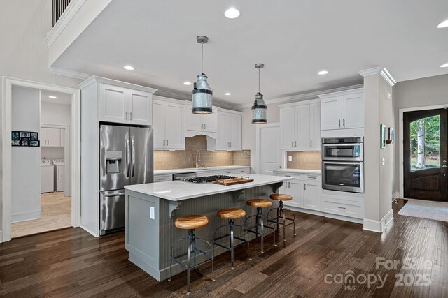 112 Nautilus Ct, Troutman, NC 28166 - kitchen with stainless steel appliances, washing machine and dryer, a sink, white cabinets, and a kitchen island