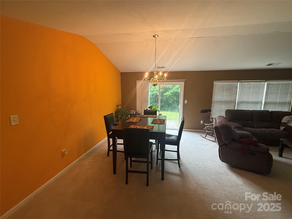 181 Mott Rd, Mooresville, NC 28115 - dining space with a chandelier, light colored carpet, baseboards, and lofted ceiling