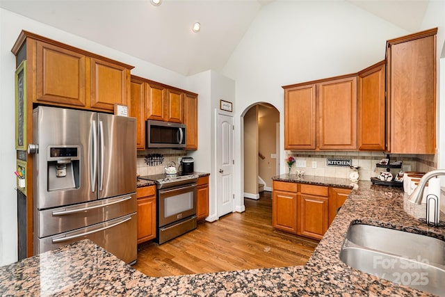 6603 Havencrest Dr, Denver, NC 28037 - kitchen featuring stainless steel appliances, a sink, arched walkways, tasteful backsplash, and light wood-style flooring