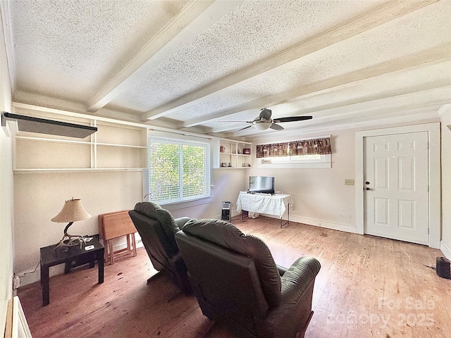 sitting room featuring a textured ceiling, beamed ceiling, plenty of natural light, and wood finished floors