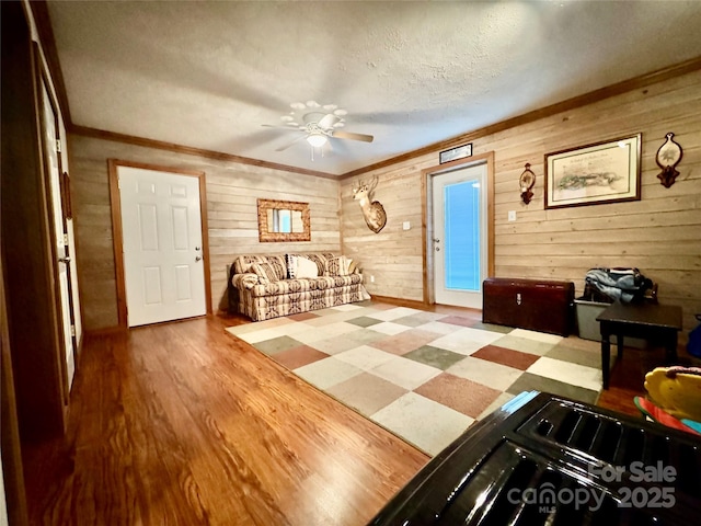 5518 Land Harbour Dr, Granite Falls, NC 28630 - living room featuring ceiling fan, a textured ceiling, wood walls, wood finished floors, and ornamental molding