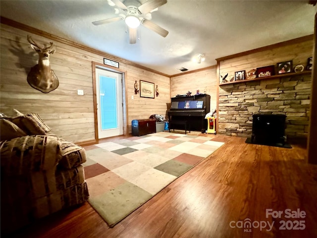 5518 Land Harbour Dr, Granite Falls, NC 28630 - living area with crown molding, a wood stove, wood walls, wood finished floors, and ceiling fan