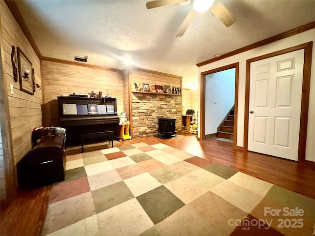 5518 Land Harbour Dr, Granite Falls, NC 28630 - living room featuring ornamental molding, a wood stove, wood walls, and stairs