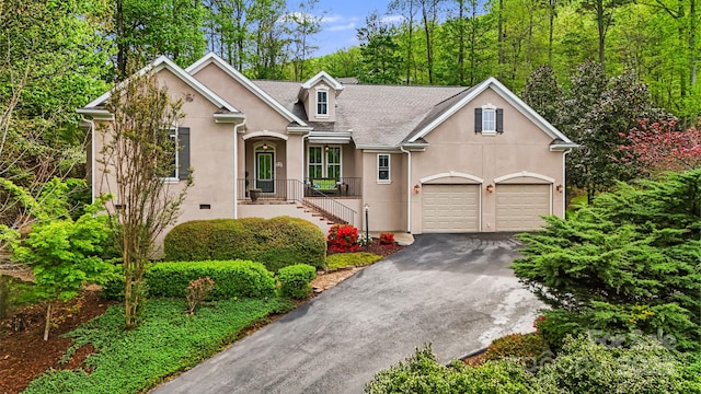 view of front of house featuring roof with shingles, stucco siding, and driveway