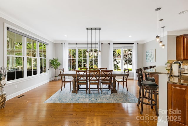 dining area featuring crown molding, a healthy amount of sunlight, and wood finished floors