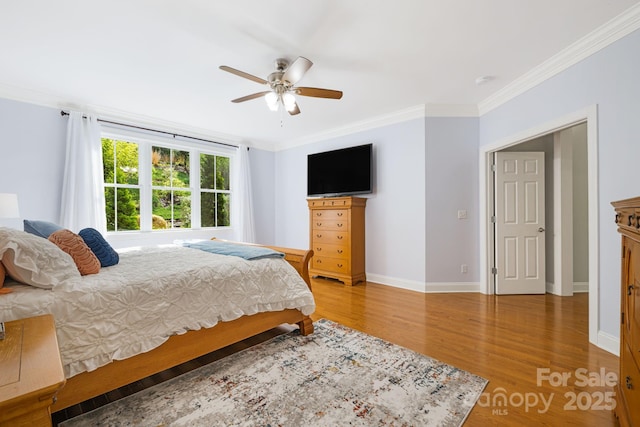 bedroom featuring crown molding, baseboards, a ceiling fan, and light wood finished floors