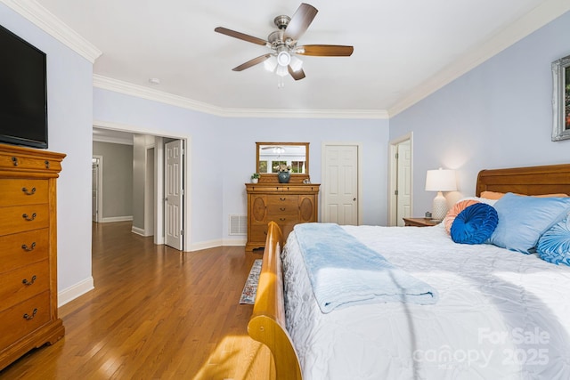 bedroom featuring wood finished floors, visible vents, baseboards, ceiling fan, and ornamental molding